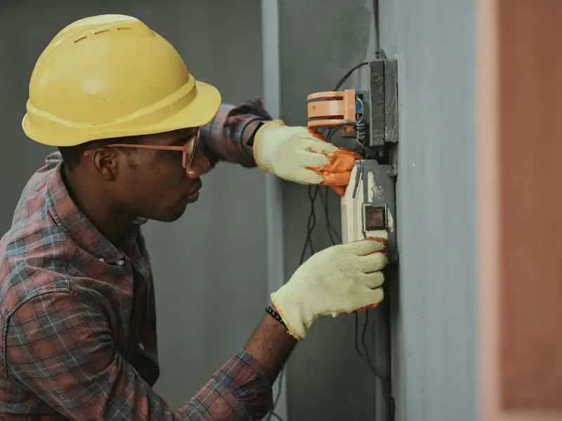 Electrician in a hard hat working on an electrical meter
