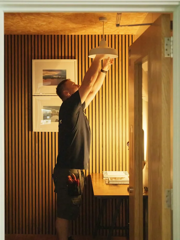 Electrician installing a pendant light fixture inside a home